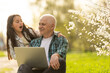 © Angelov - grandfather and granddaughter with laptop in the garden