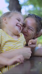 vertical video: closeup of cute little girl plays with mom while sitting in the park. close-up of mo