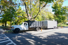 A White Landscaping Truck With A Long White Enclosed Trailer Trailer Seen On A Shady Residential Asphalt Street