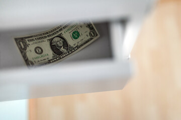 Top view of the last one dollar note lying in an open drawer.