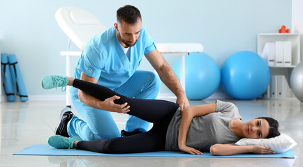 Poster - Physiotherapist working with female patient in rehabilitation center