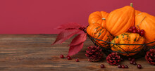 Basket With Fresh Pumpkins, Berries And Fir Cones On Wooden Table Against Color Background With Space For Text