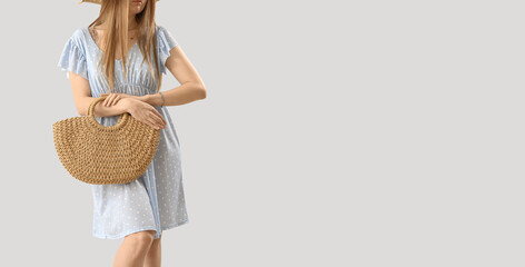 Wall Mural - Stylish young woman with natural rattan bag on light background with space for text