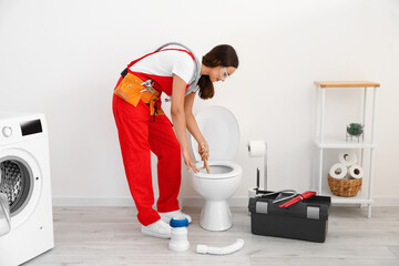 Wall Mural - Female plumber fixing toilet bowl in restroom