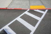 Freshly Painted White Crosswalk Marking Leading To A Yellow Painted ADA Sidewalk Access In A Fire Lane
