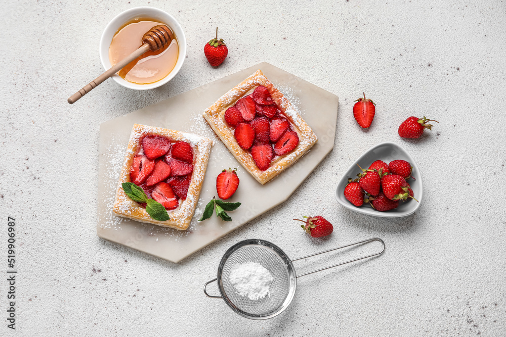 Board with sugar powdered puff pastry, strawberry and honey on light background