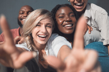 Canvas Print - Group of friends, men and women having fun, smiling and being carefree while bonding together in the city. Young, happy, smiling and cheerful female making a hand sign while posing for a photo