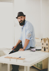 Wall Mural - Portrait of male designer in hat with blueprints at desk