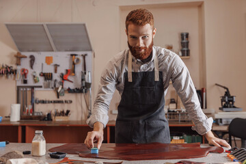 Wall Mural - Man master shoemaker tailor covers skin with protective layer for further work