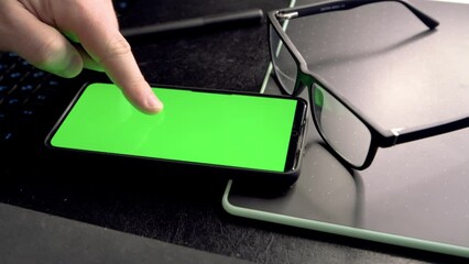 Poster - Man unlocking and using mobile phone at his working place. 4k video footage with green screen smartphone