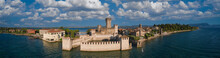 Panoramic Aerial View Of Scaligero Castle At Sunrise. Historic Part Of The City Of Sirmione View On Lake Garda, Italy. Panorama Of The Historic Castle On The Water On Lake Garda.