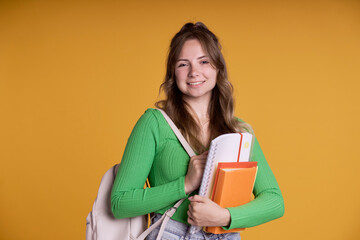 portrait of smiling caucasian student girl holding school books and wearing schoolbag