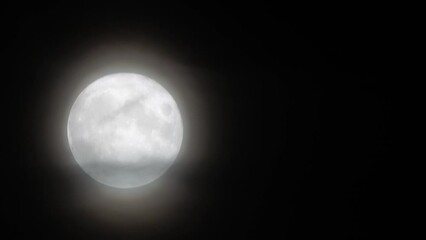 Wall Mural - Glowing huge full moon as seen from earth through the clouds against starry night sky. Large full moon moves across the sky, moon makes its way from bottom left frame to top right.