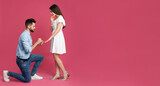 Fototapeta  - Man with engagement ring making marriage proposal to girlfriend on pink background, space for text. Banner design