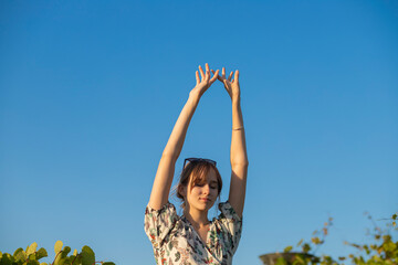 beautiful girl against the sky.  arms raised lightly above the head against the sky.  feminine gentle hands.  photo for advertising cosmetic services.
  A beautiful fashion model girl enjoys nature, b