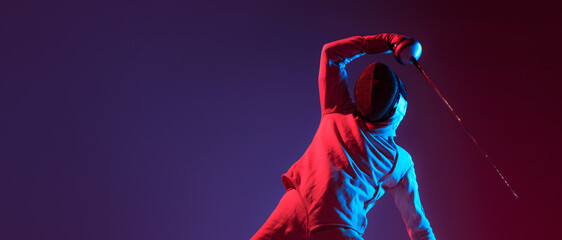 Wall Mural - Male fencer with smallsword practicing fencing isolated on purple background in neon light. Sport, energy, skills, achievements