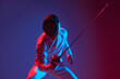 Male fencer with smallsword practicing fencing isolated on purple background in neon light. Sport, energy, skills, achievements