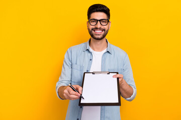 Canvas Print - Photo of young guy smiling holding notepad pen waiting you signature write for new delivery isolated on yellow color background