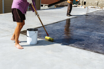 A worker varnishes the floor surface on an outdoor veranda. Finishing of the adjacent territory. unrecognizable person