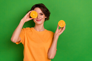 Poster - Photo of sweet cute young woman dressed orange t-shirt holding citrus slices cover eye empty space isolated green color background