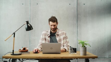 Poster - Professional Creative Man Sitting at His Desk in Office Working on a Laptop Computer. Stylish Clean Office Space Design Perfect for Productivity, Effectiveness and Vision. Medium Shot