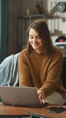 Poster - Smiling Young Woman Working from Home on Laptop Computer in Her Sunny Cozy Apartment, Relaxes and Leans Back on a Sofa. Successful Creative Female Entrepreneur Happy After Finishing Remote Work