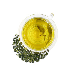 Green tea in glass cup on transparent saucer with scattering dry tea leaves isolated on white background top view