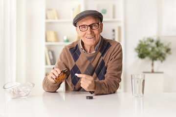 Smiling elderly man sitting at home and taking a pill