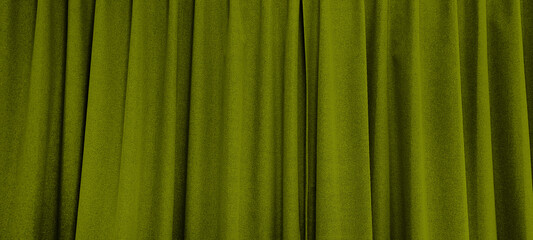 close up view of green olive curtain in thin and thick vertical folds made of black out sackcloth fabric, panoramic view of drapery use as background. abstract theatre backgrounds and wallpapers.