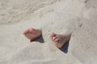 Child feet buried in the sand on the beach