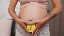Parenthood And Pregnancy Concept. It's A Girl. Pregnant Unrecognizable Woman Showing Her Nude Pregnant Belly With A Yellow Sticky Note To The Camera. High Quality 4k Footage