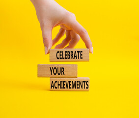 Celebrate your achievements symbol. Concept words Celebrate your achievements on wooden blocks. Beautiful yellow background. Businessman hand. Business concept. Copy space