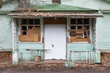 entrance to an old house with broken and boarded up windows