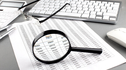 Poster - Office desk workplace with keyboard, charts and magnifier on grey table. Top view with