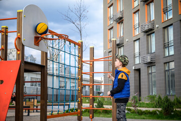 Wall Mural - Portrait of a boy with a basketball on a basketball court. The concept of a sports lifestyle, training, sport, leisure, vacation