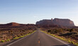 Scenic Road in the Dry Desert with Red Rocky Mountains in Background.