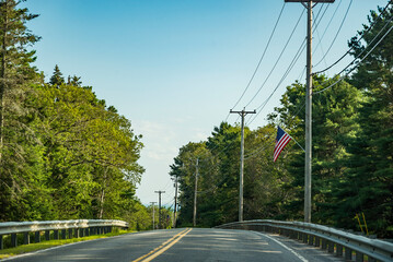 Country main road fading into the horizon distance on a blue sky day, Maine