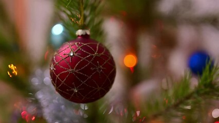 Wall Mural - Christmas tree decorated with red glass ball on christmas spruce branch on background bokeh of flickering light bulbs garlands. Happy New Year festival mood. Positive emotion.