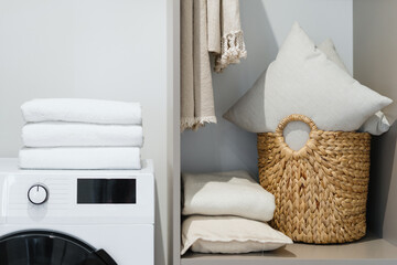 Washing machine standing in wardrobe with laundry basket