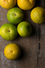 Wall Mural - sweet orange fruits scattered on rustic wooden table top, taken directly from above with space for text