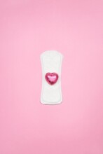 White Sanitary Napkin With A Pink Candy On Bright Color Background