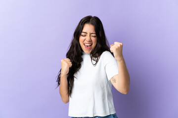 Wall Mural - young caucasian woman isolated on purple background celebrating a victory