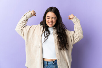Wall Mural - young caucasian woman isolated on purple background doing strong gesture