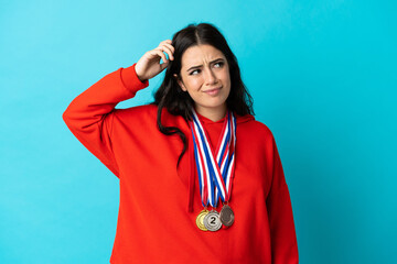 Young woman with medals isolated on white background having doubts and with confuse face expression