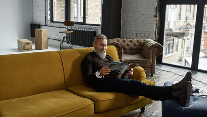 Wall Mural - Grey hair man reading journal on sofa at home