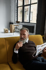 Wall Mural - Thoughtful man drink cognac and read newspaper