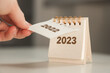 Leinwandbild Motiv a woman's hand turns over a calendar sheet. year change from 2022 to 2023