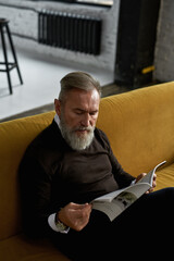 Wall Mural - Elderly caucasian man reading journal on sofa