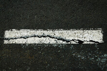 Worn White Road Line On Cracked Asphalt Close-up
