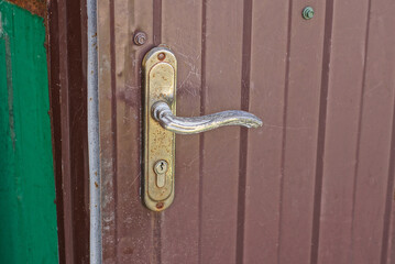 Canvas Print - one gray iron doorknob on a brown metal door in the street